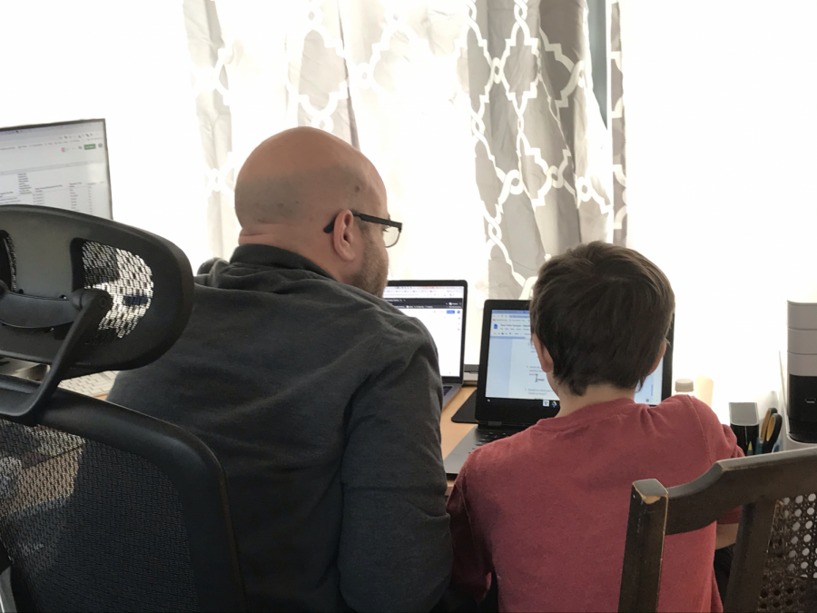 Albert Spiegel works with his 9-year-old son, Ryan Pinto-Spiegel, on third grade science. Both are working at a desk at home.