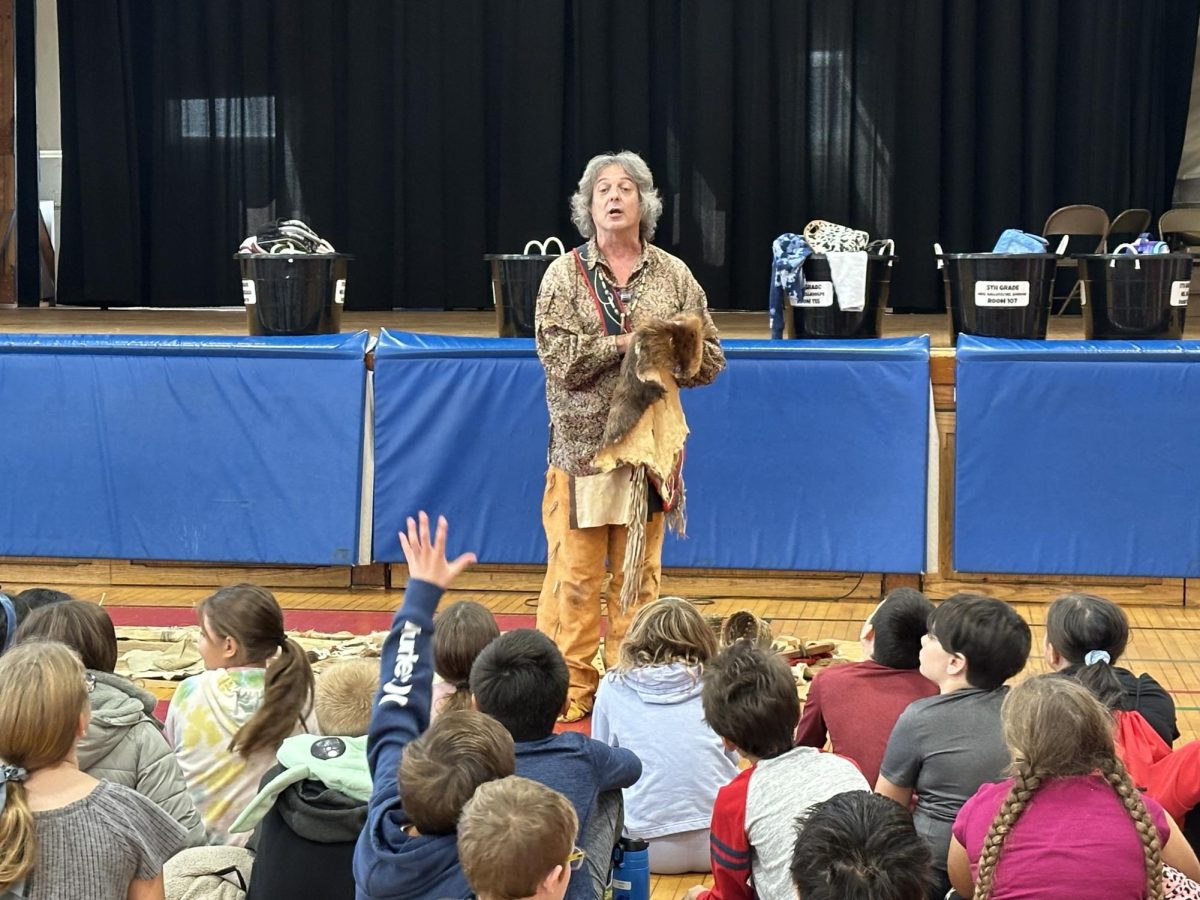 The instructor at the assembly teaches the fourth grade students about the everyday life of the Lenape people.  He is showing them a beaver skin that was hunted and used for clothing,  The students had the opportunity to feel the skin and fur.
