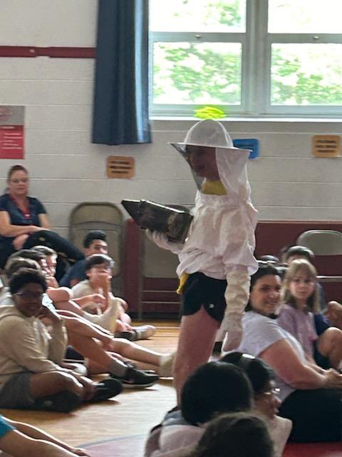 Norah Smith. a fifth-grade student, tries on the protective clothing bee keepers wear when collecting honey from hives.