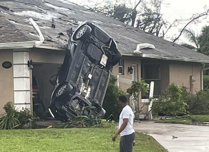 The winds off the west coast of Florida were strong enough to overturn this car into a nearby house.