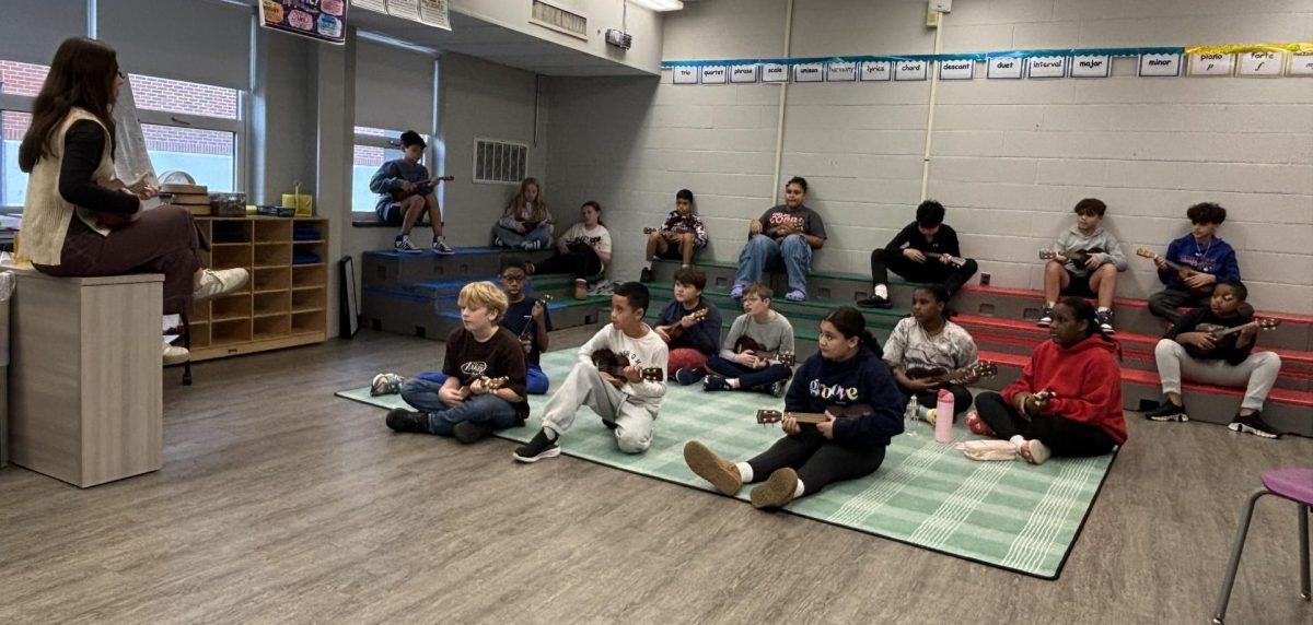 Rayna Fox teaches a music class how to use the ukelele.