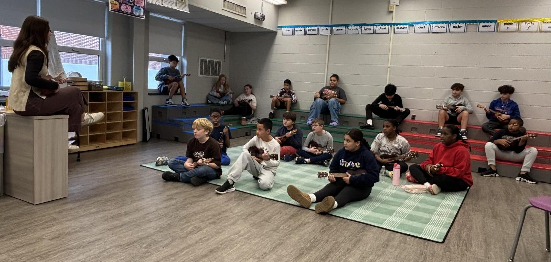 Rayna Fox teaches a music class how to use the ukelele.