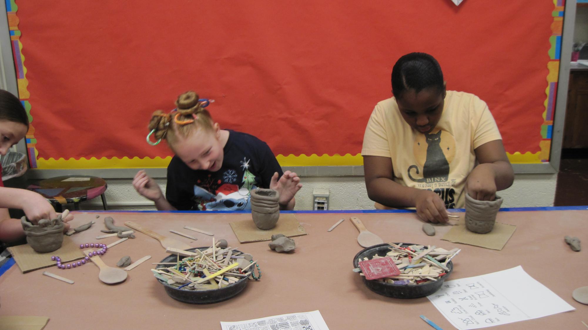 Sixth graders work with a college art professor on their clay skills.