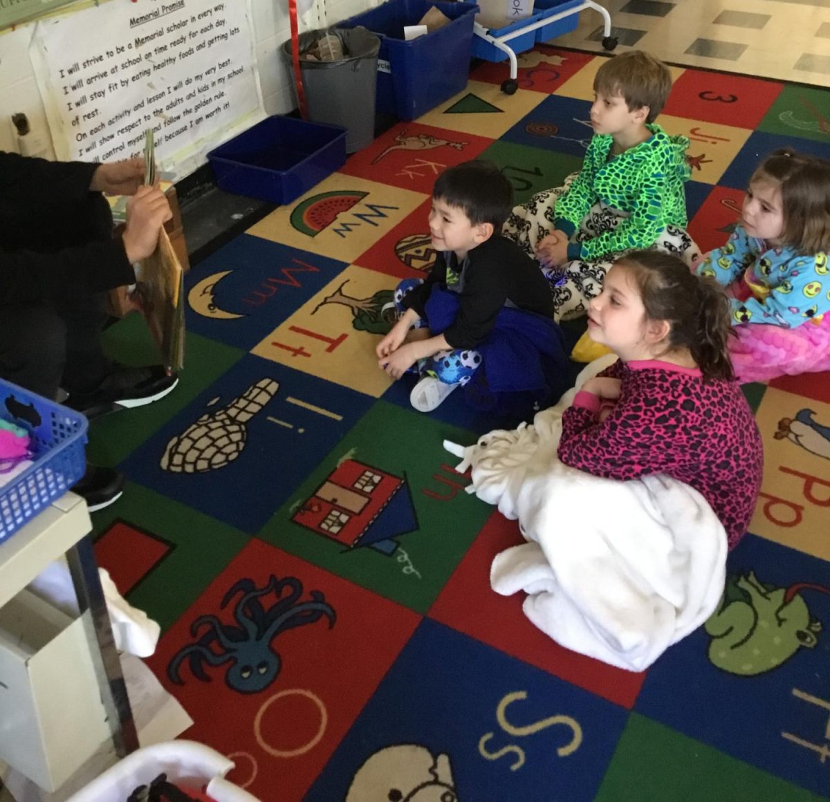 Younger students at Memorial School listen to a story read aloud by a teacher.